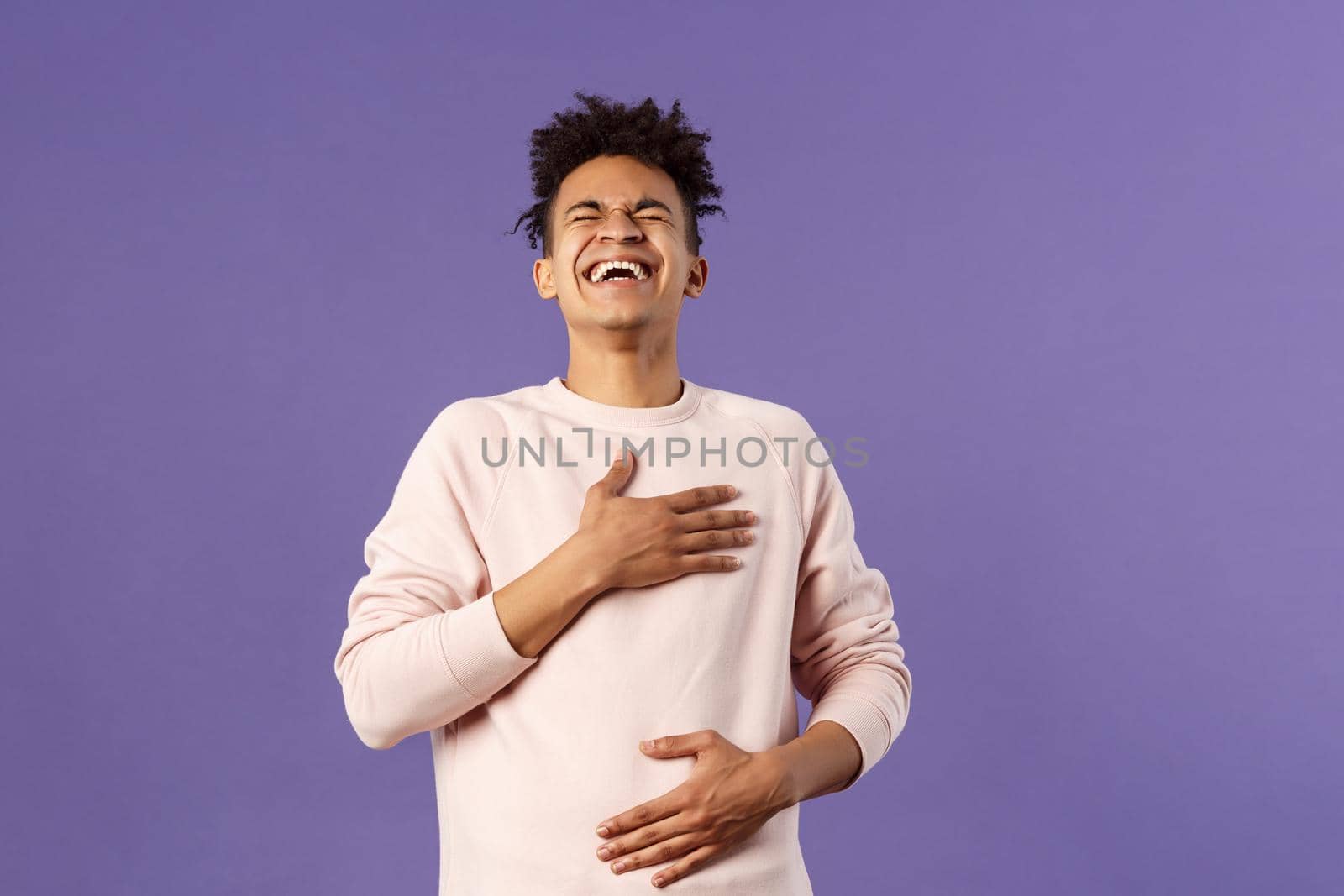 Portrait of cheerful, happy young hipster guy laughing out loud from hilarious joke, watching awesome stand-up performer, chuckle and touchign chest, bending backwards from laugh.