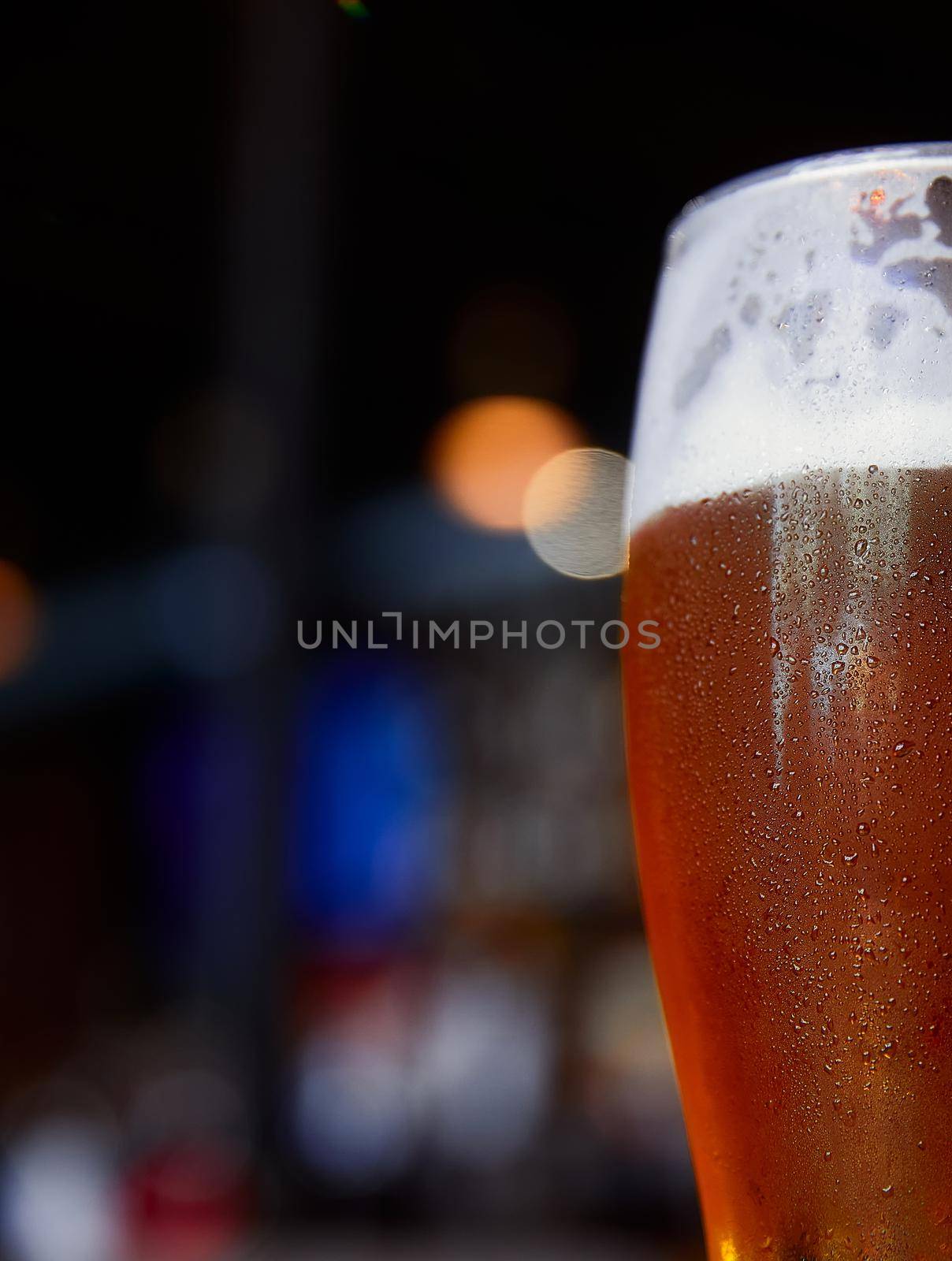 Glass of beer on a table in a bar on blurred bokeh background.