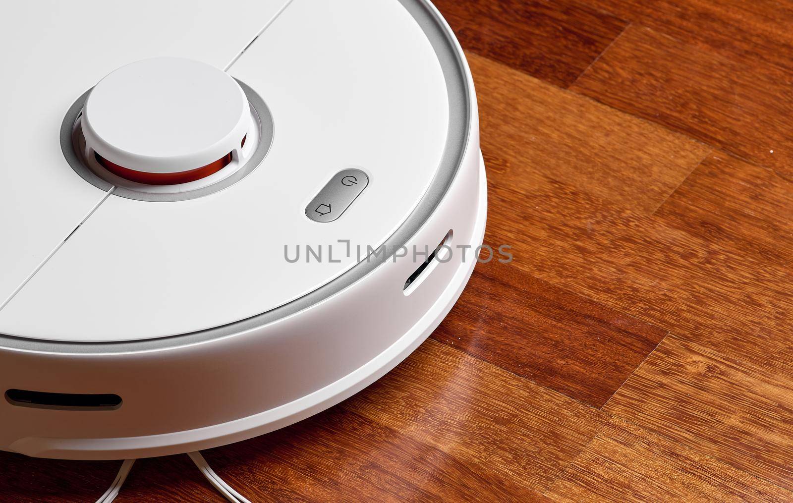 Smart Robot Vacuum Cleaner on wood floor. Robot vacuum cleaner performs automatic cleaning of the apartment at a certain time. Smart home.