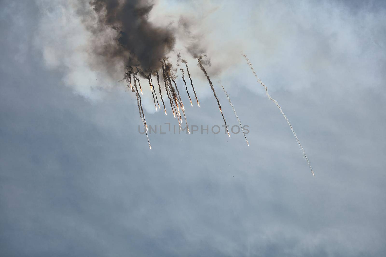 Aircraft fighter flies and shoots heat guns in the blue sky. Fighter shoots off heat traps during the maneuver. A fighter during a demonstration aerobatics by EvgeniyQW