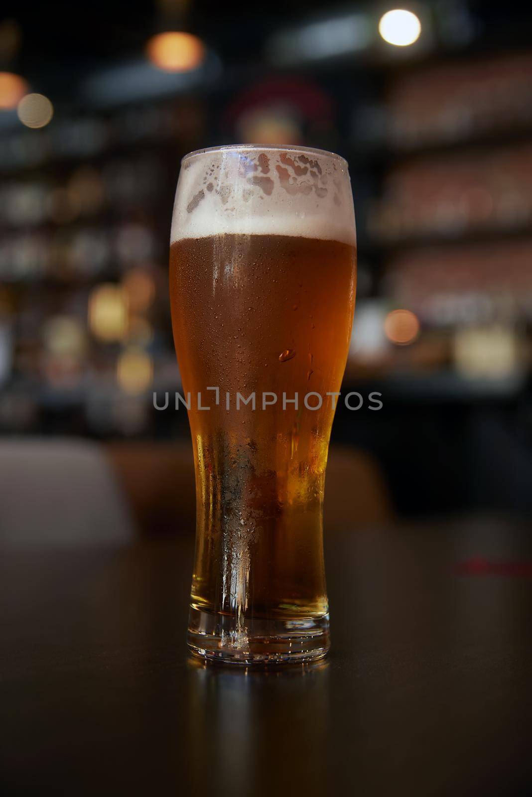 Glass of beer on a table in a bar on blurred bokeh background.