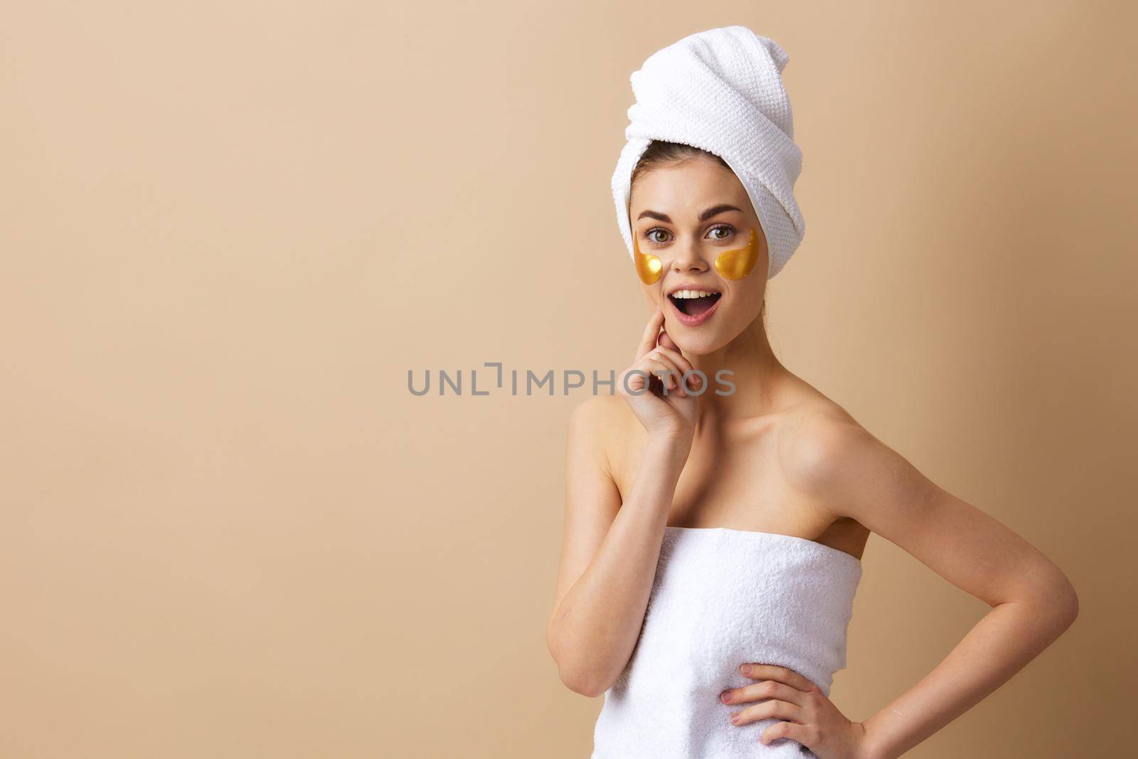 young woman with a towel on his head gesturing with his hands skin care beige background. High quality photo