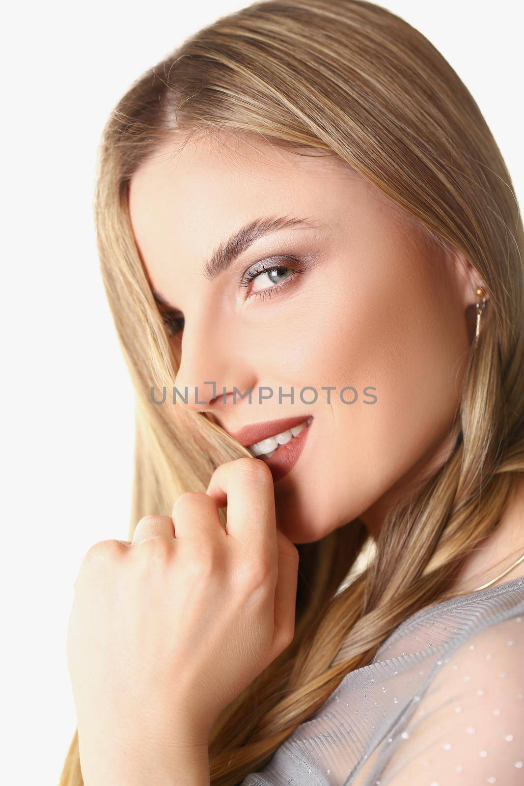 Portrait of flirting young stylish blonde woman posing on white background in studio. Professional model, lovely makeup. Modeling, beauty, emotion concept