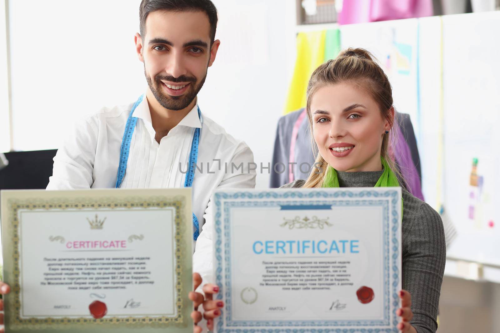 Portrait of man and woman team hold certificate, confirmation of high quality and service. Creating fashionable clothes in small studio. Fashion concept