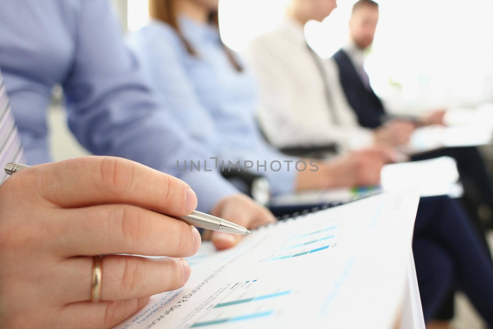 Close-up of male hand writing notes in papers on meeting, manager in conference room listen to discussion about business project. Company meeting concept