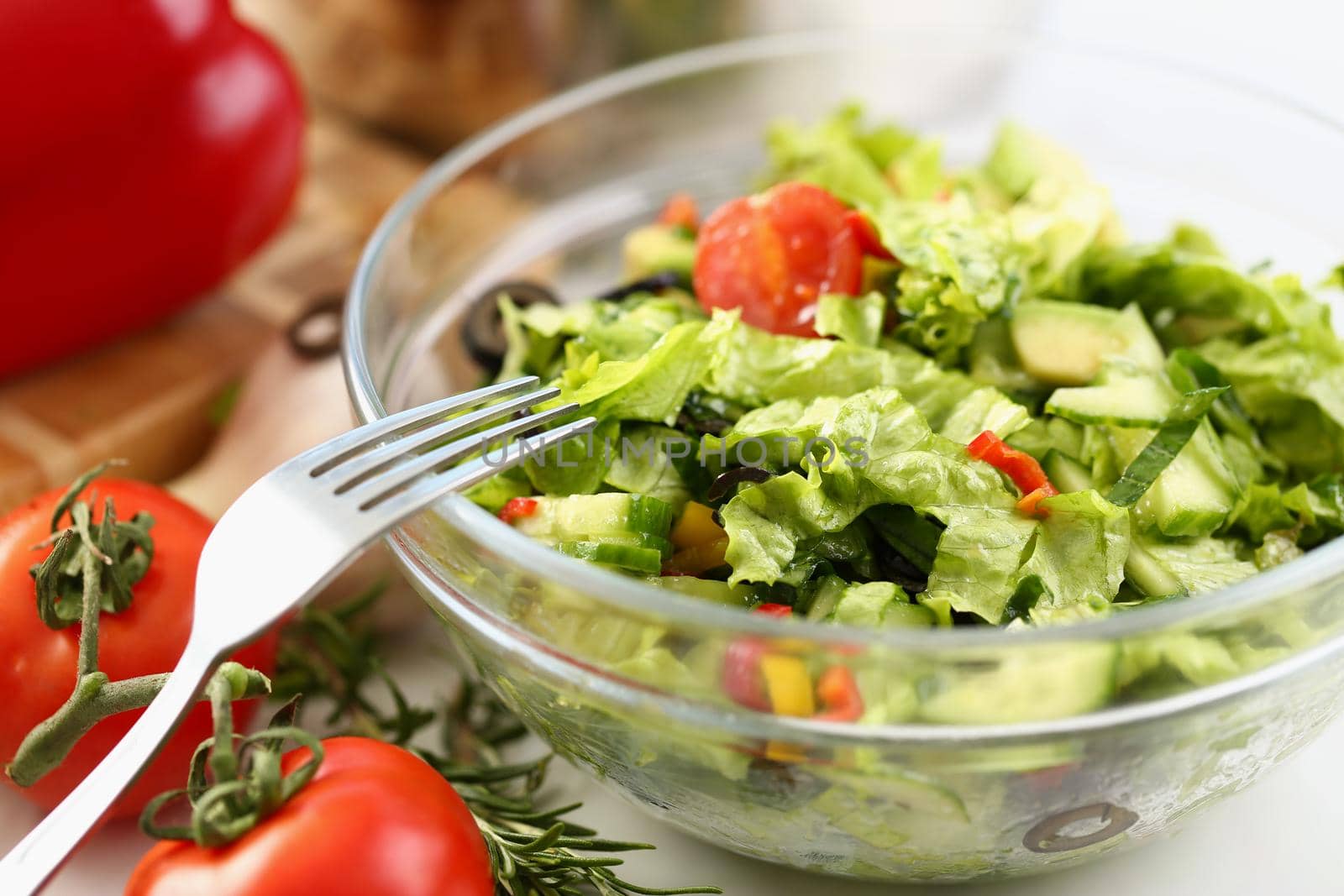 Close-up of delicious fresh greek salad with fresh lettuce leaves, tomato, cucumber, feta, olives, pepper, and lime. Meal served on table. Cooking concept