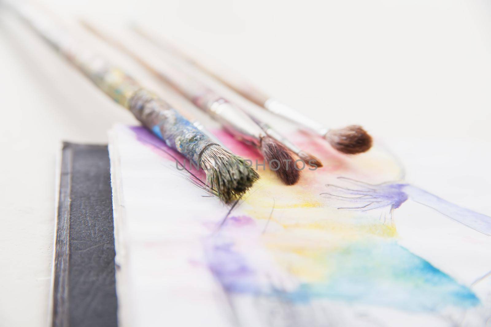 paint brushes lying on colorful painted background
