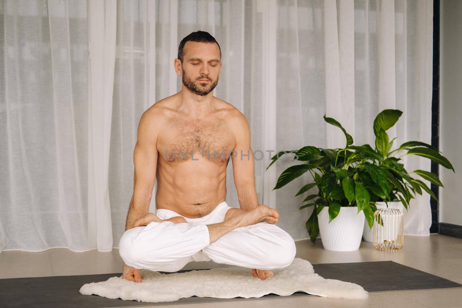 a man with a bare torso does yoga in a fitness room. the concept of a healthy lifestyle.