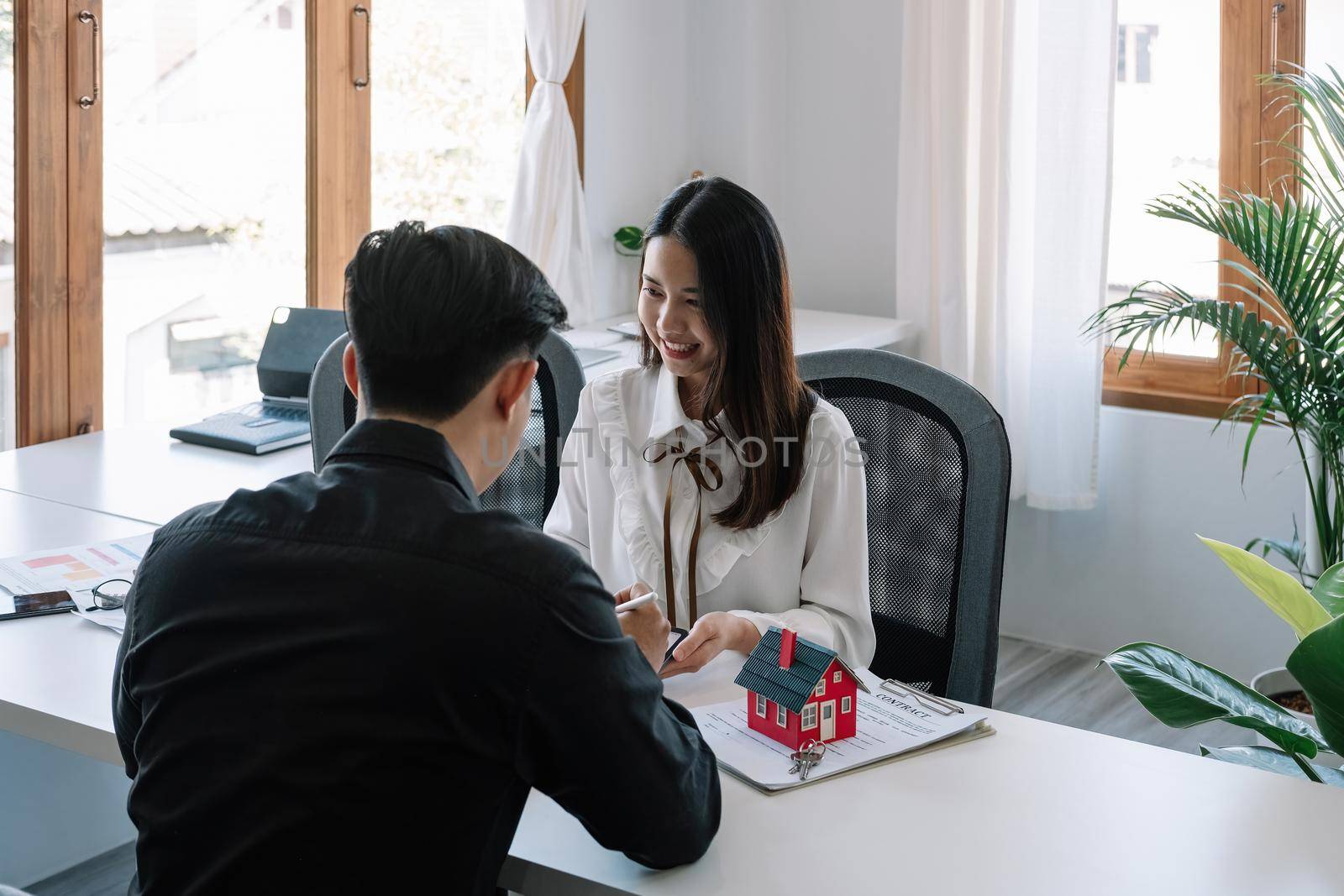 Real estate company to buy houses and land are delivering keys and houses to customers after agreeing to make a home purchase agreement and make a loan agreement. Discussion with a real estate agent.