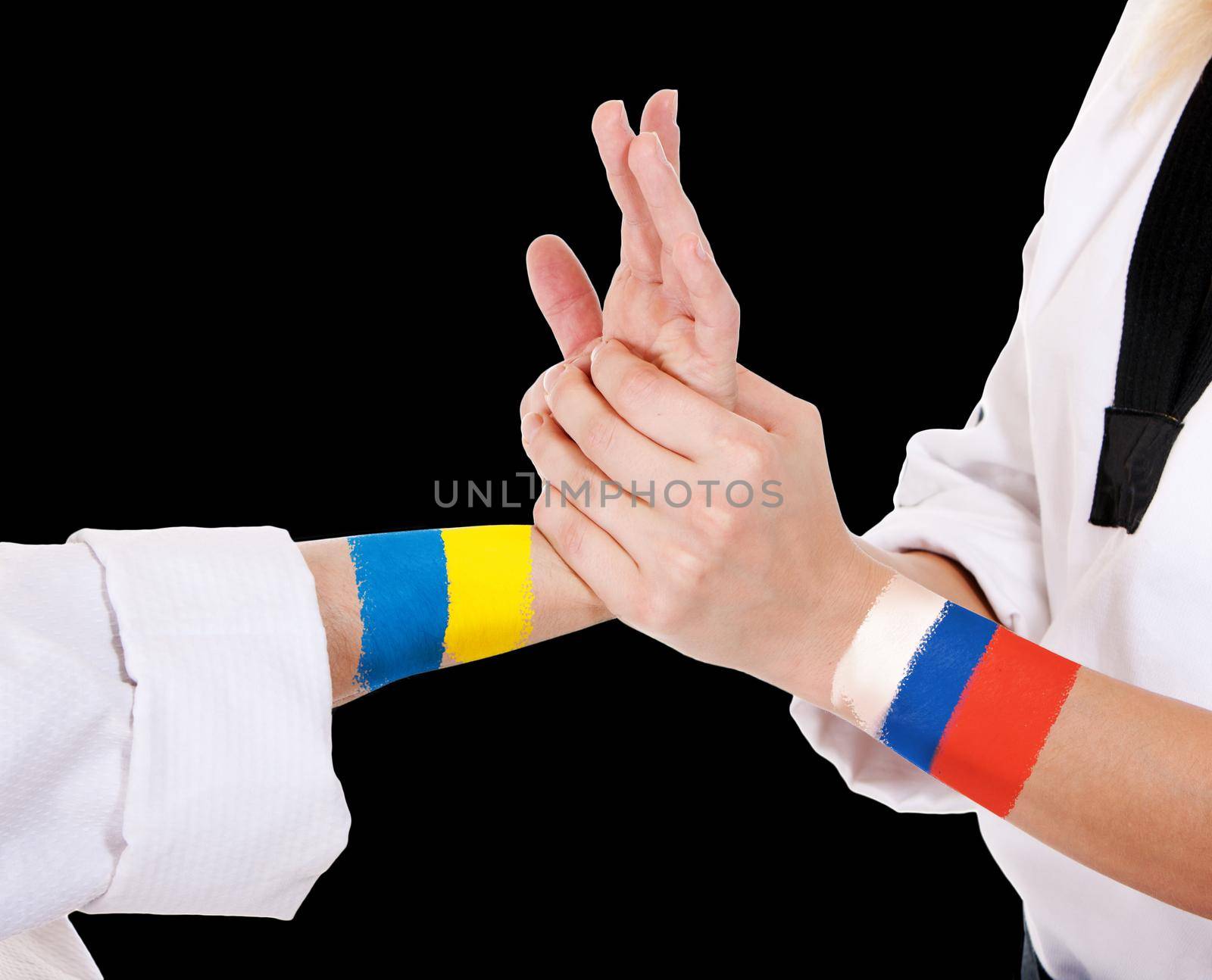 Two fighting hands of representatives of different countries Ukraine and Russia. Hold hands of two fighting people isolated on black background.