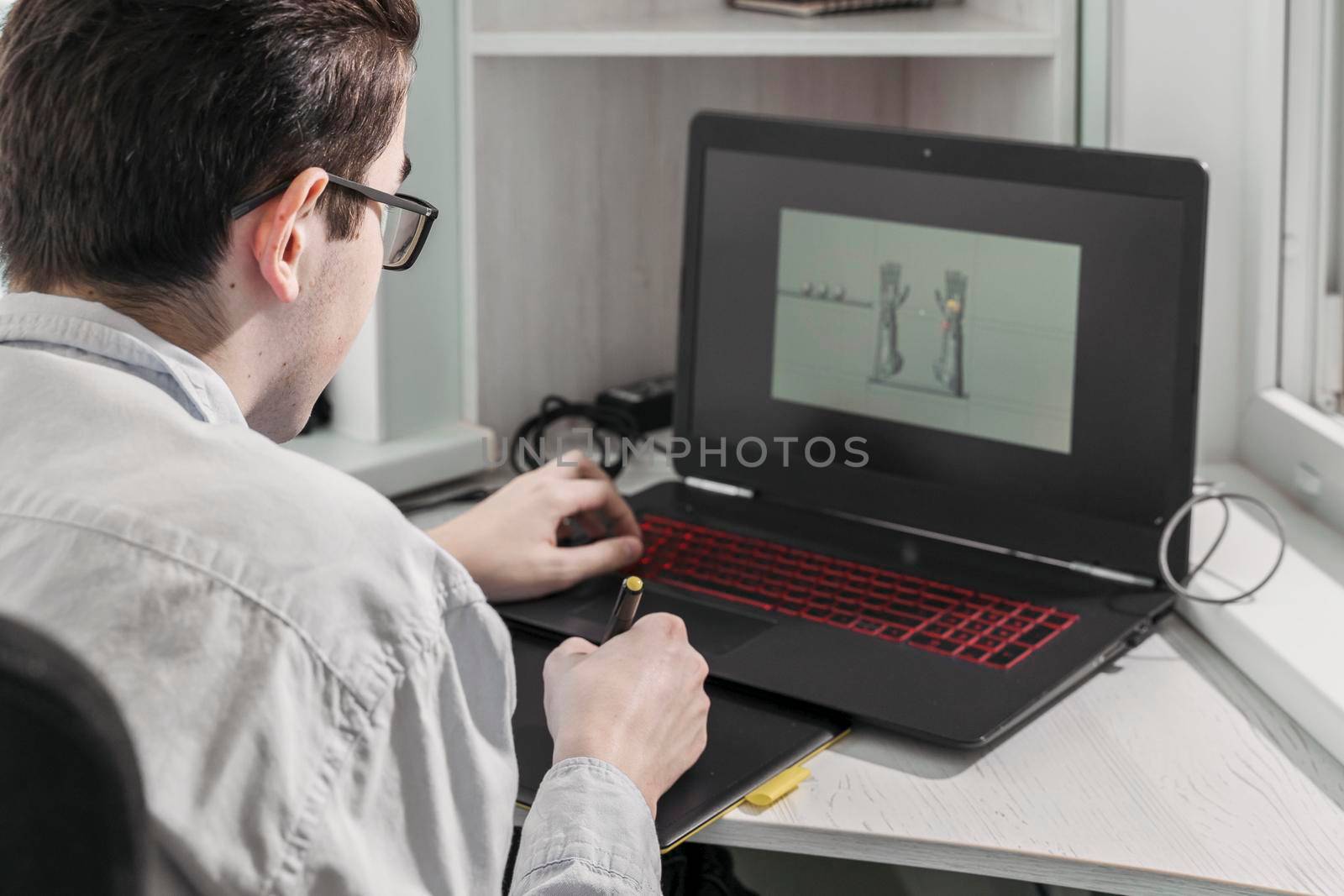 man creates video games. a designer creates a 3d model on his laptop