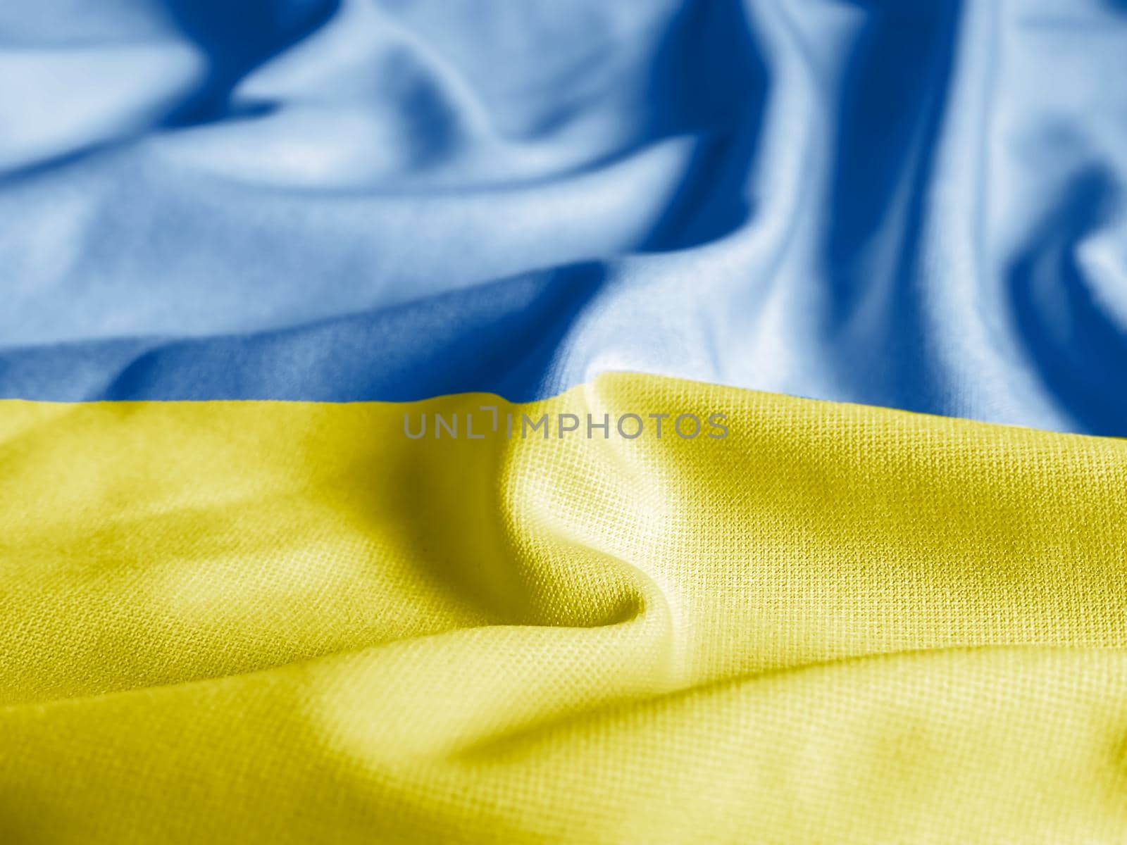Close up of the Ukraine flag on a ruffled mesh fabric. Curves and folds of the satin fabric with texture. Selective focus and depth of field. Democracy and politics.