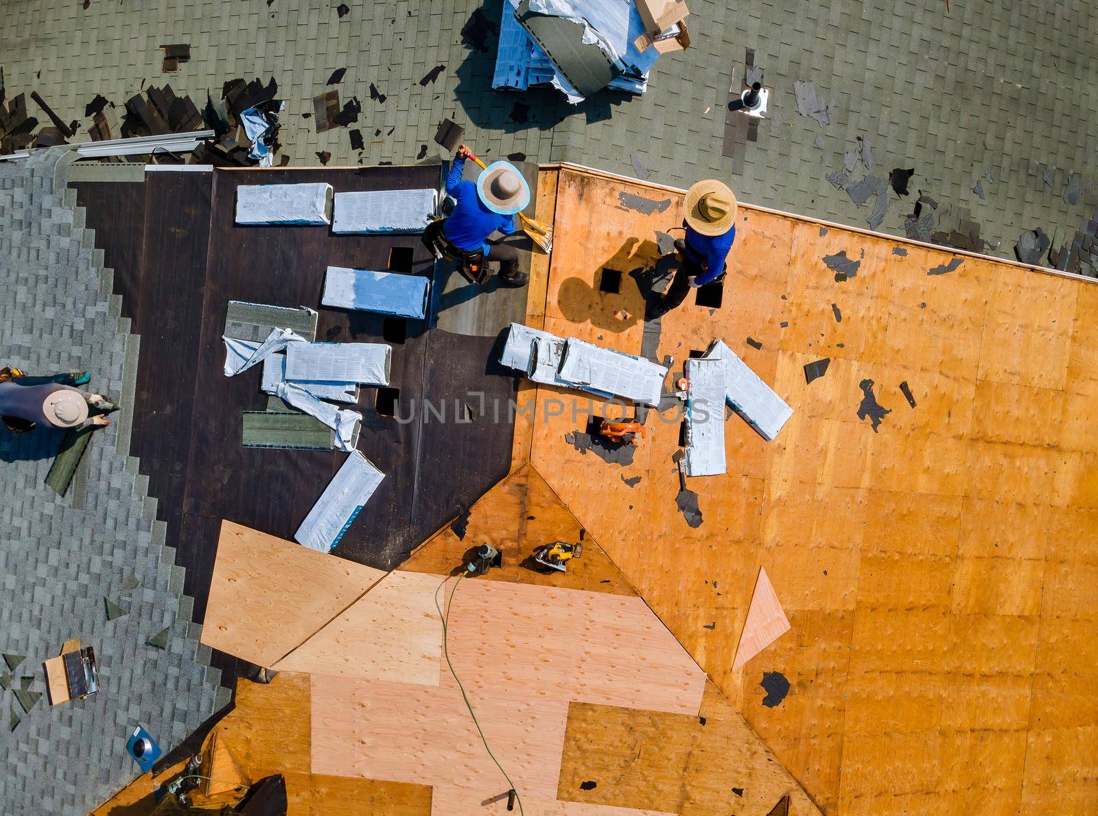 Aerial top view of construction roofer installing roof tiles at house building site at work installing roof shingles
