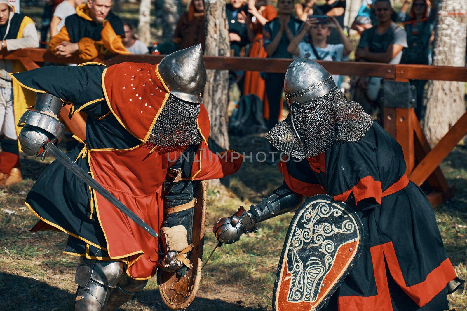 Two knights fight with swords. The knight's shield depicts a black wolf. Reconstruction of medieval battles during the festival of historical clubs. Bishkek, Kyrgyzstan-October 13, 2019.