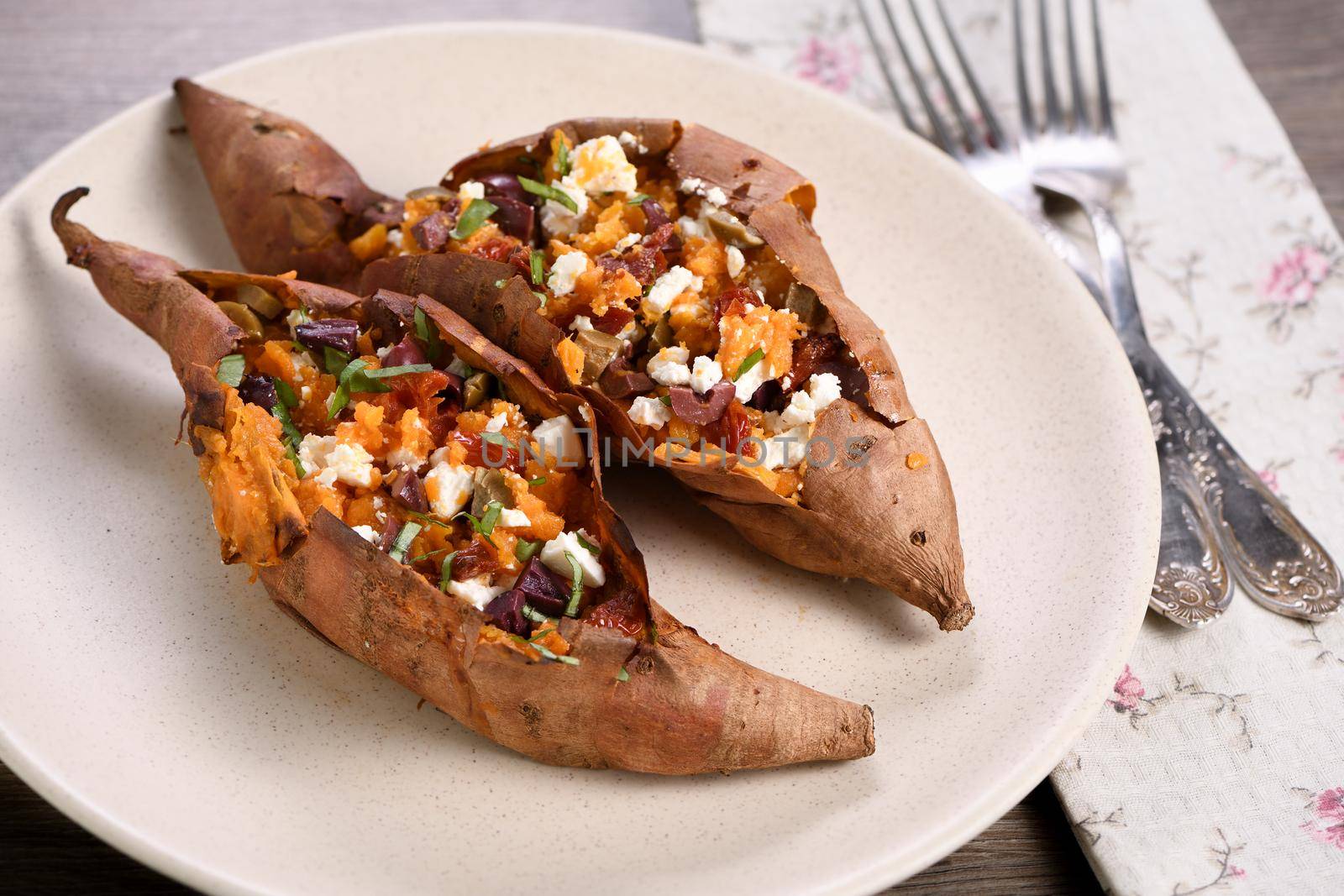 Baked sweet potato stuffed with chopped sun-dried tomatoes, olives, feta cheese and basil with aromatic dressing