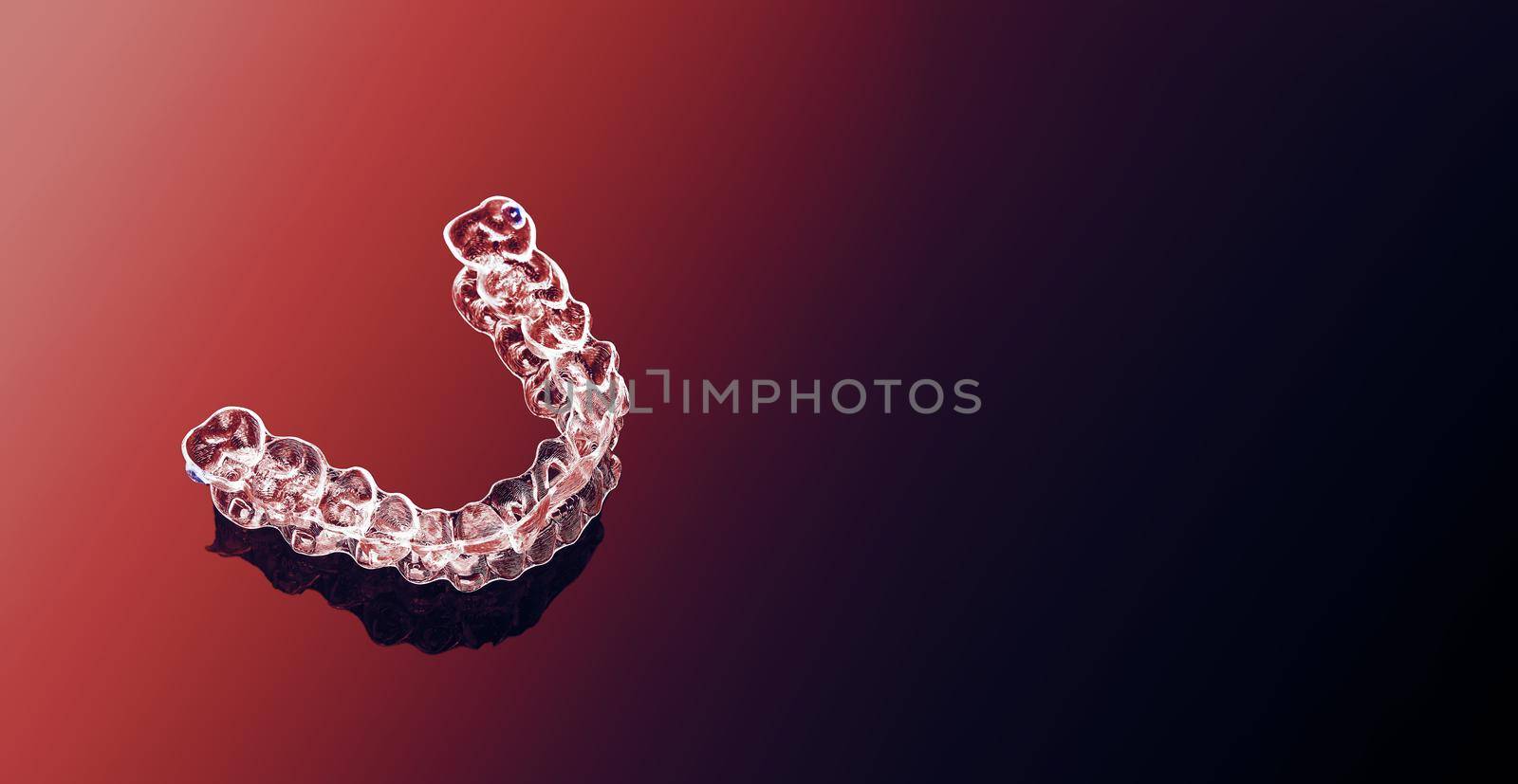 Invisible orthodontics cosmetic brackets on gradient background, tooth aligners, plastic braces. Modern teeth retainers created on a 3d printer. A way to have a beautiful smile and white teeth.