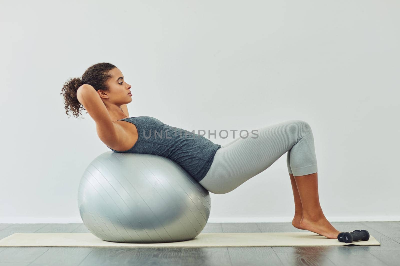 Studio shot of an attractive young woman working out against a grey background.