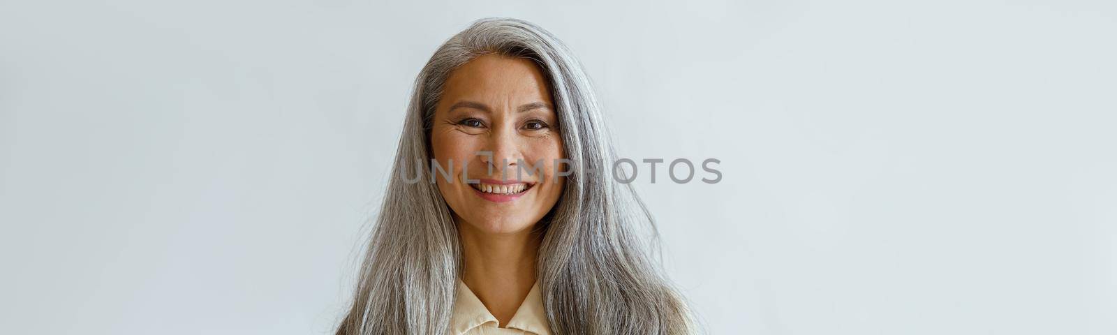 Portrait of smiling Asian woman with hoary hair and crossed arms on grey background by Yaroslav_astakhov