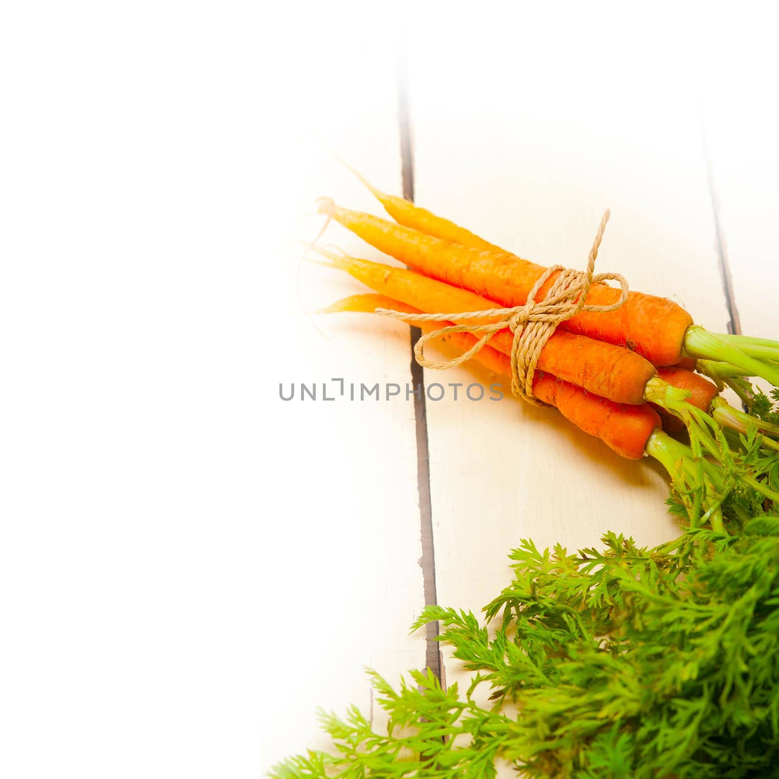 fresh baby carrots bunch tied with rope on a rustic table