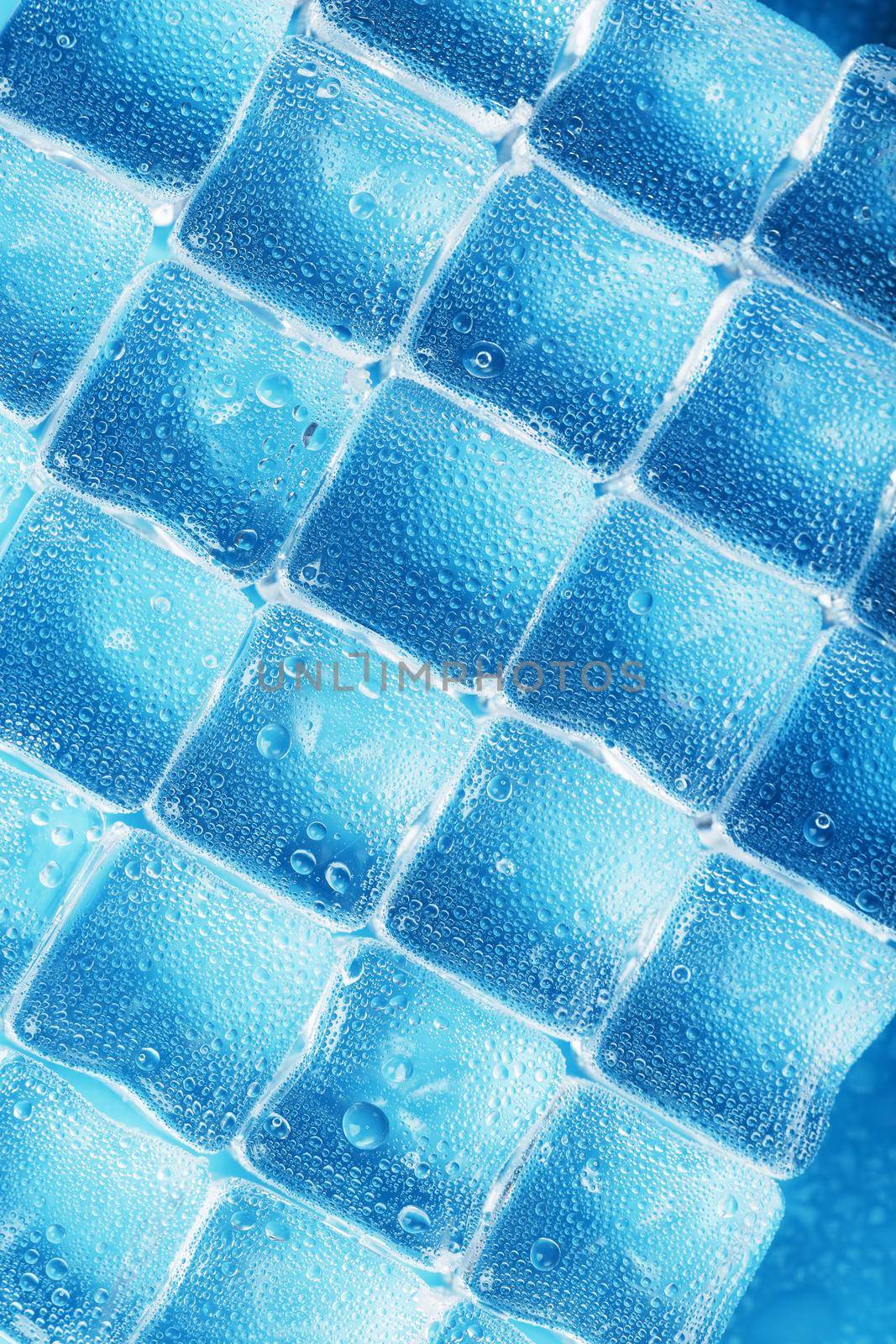 Ice made of cubes lined up with drops on a blue background