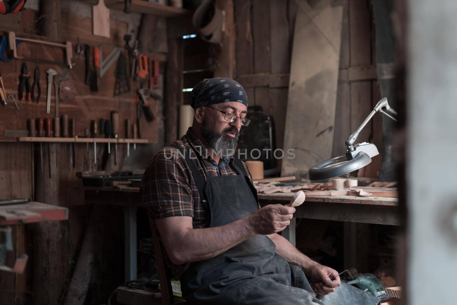 Spoon master in his workshop with wooden products and tools. High quality photo