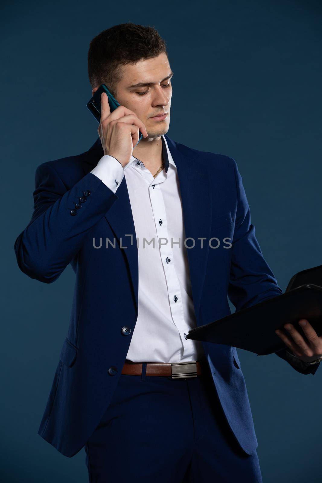 A businessman is talking on a cell phone. The man is dressed in a suit. by fotodrobik