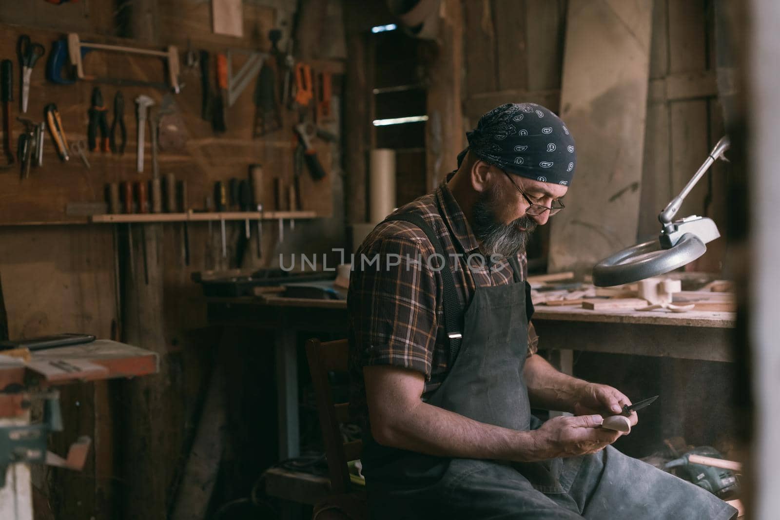 Spoon master in his workshop with wooden products and tools. High quality photo