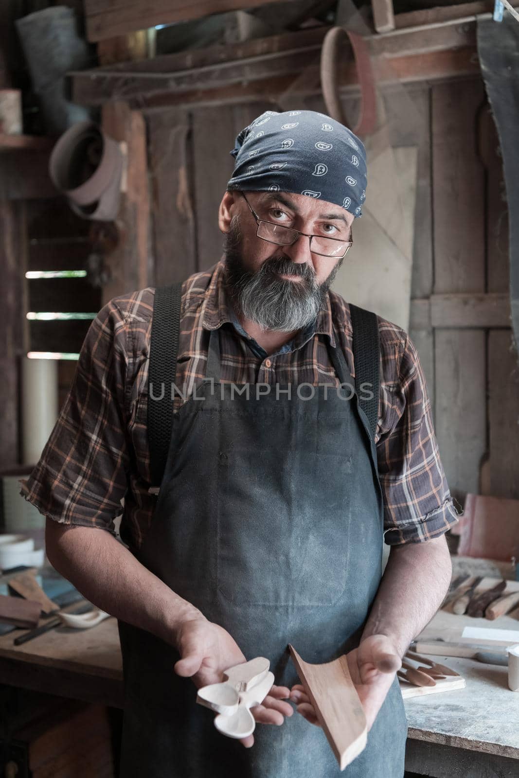 Spoon master in his workshop with wooden products and tools. High quality photo