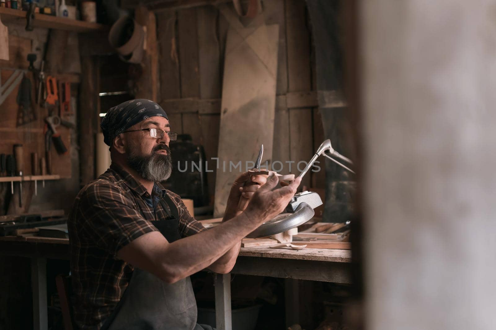 Spoon master in his workshop with wooden products and tools. High quality photo