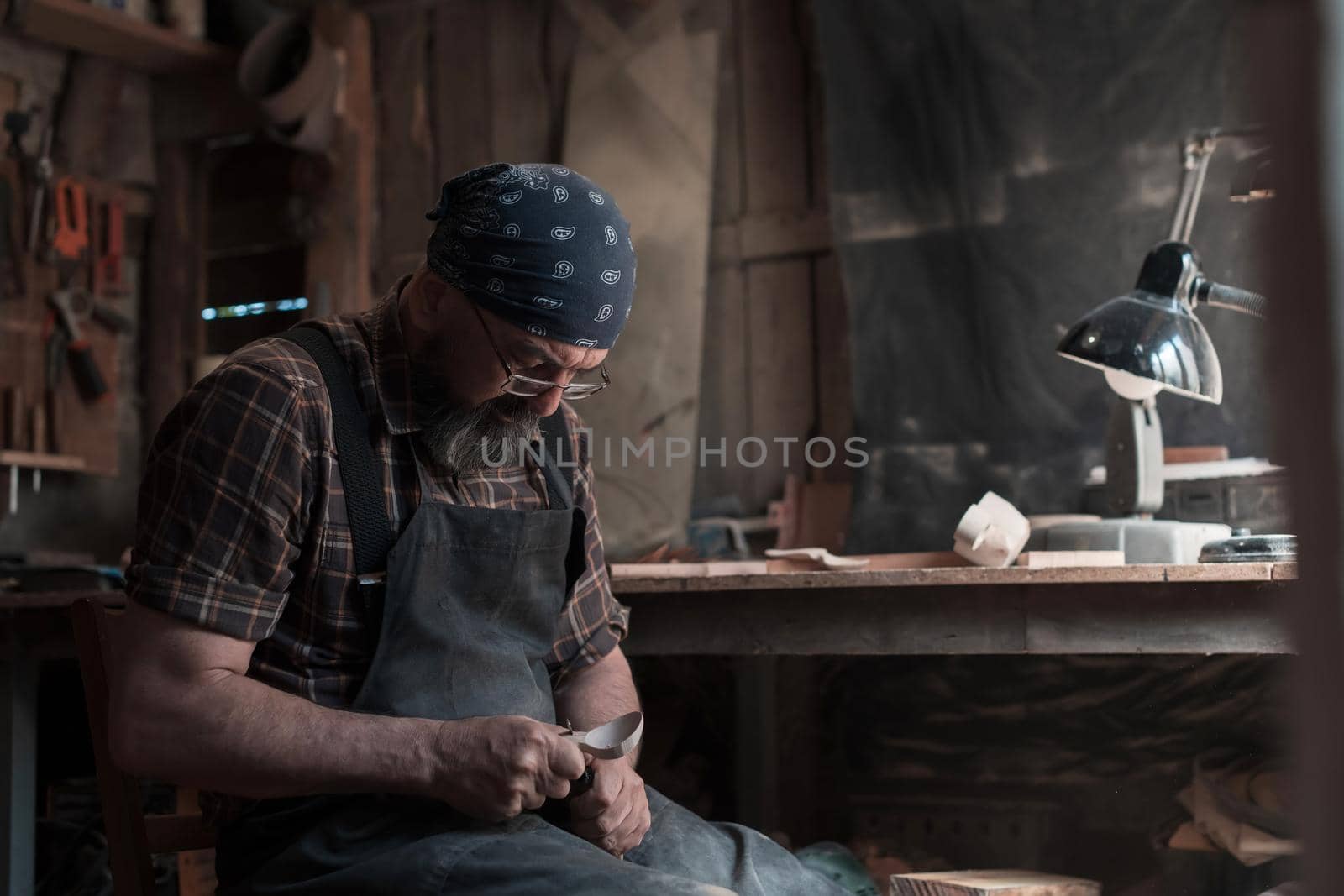 Spoon master in his workshop with wooden products and tools by dotshock