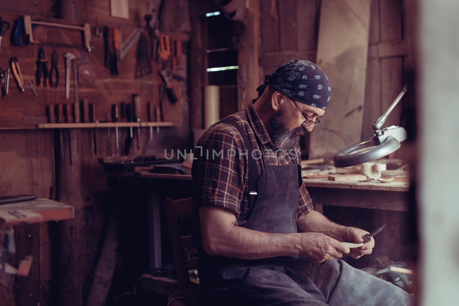 Spoon master in his workshop with wooden products and tools by dotshock