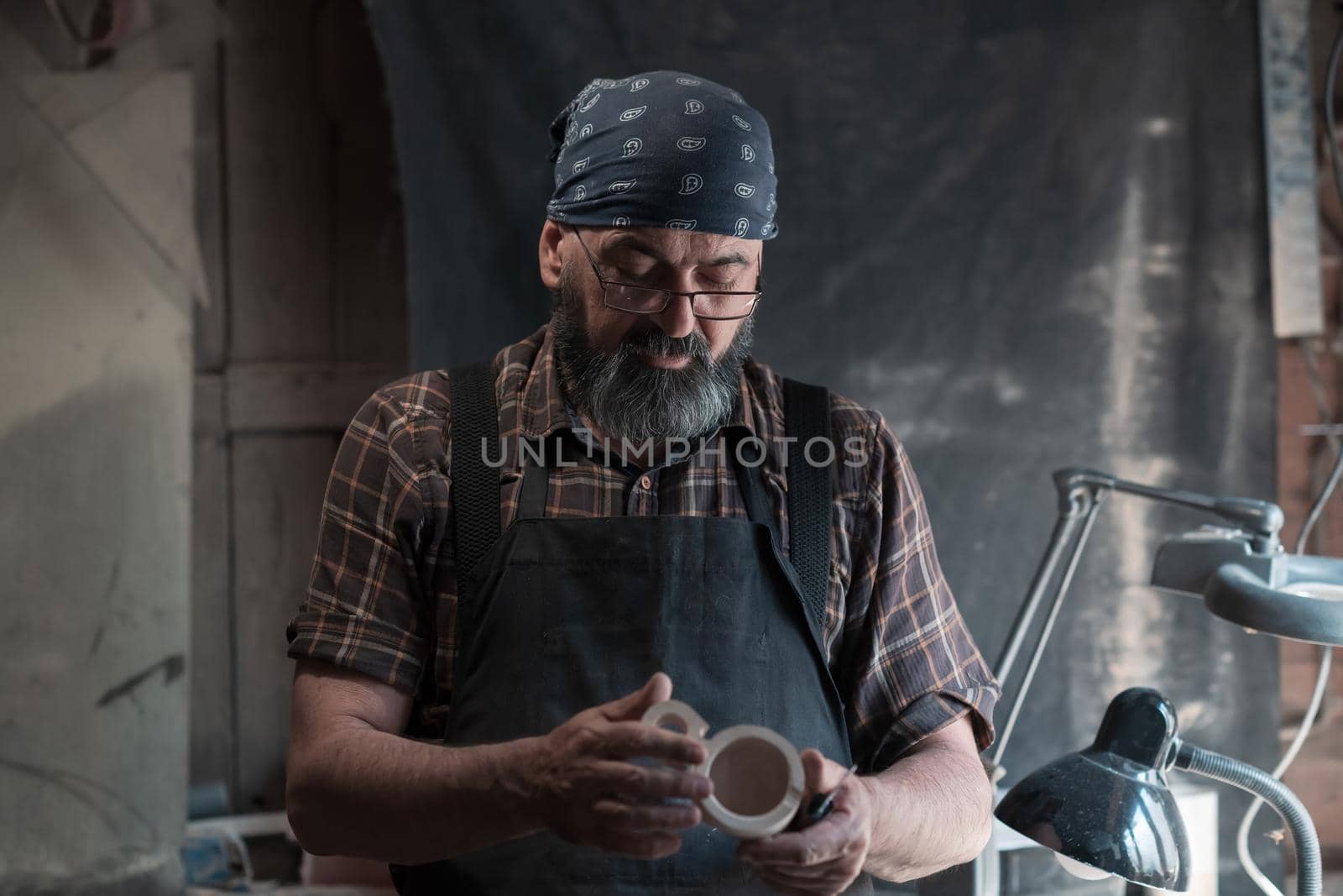 Spoon master in his workshop with wooden products and tools by dotshock