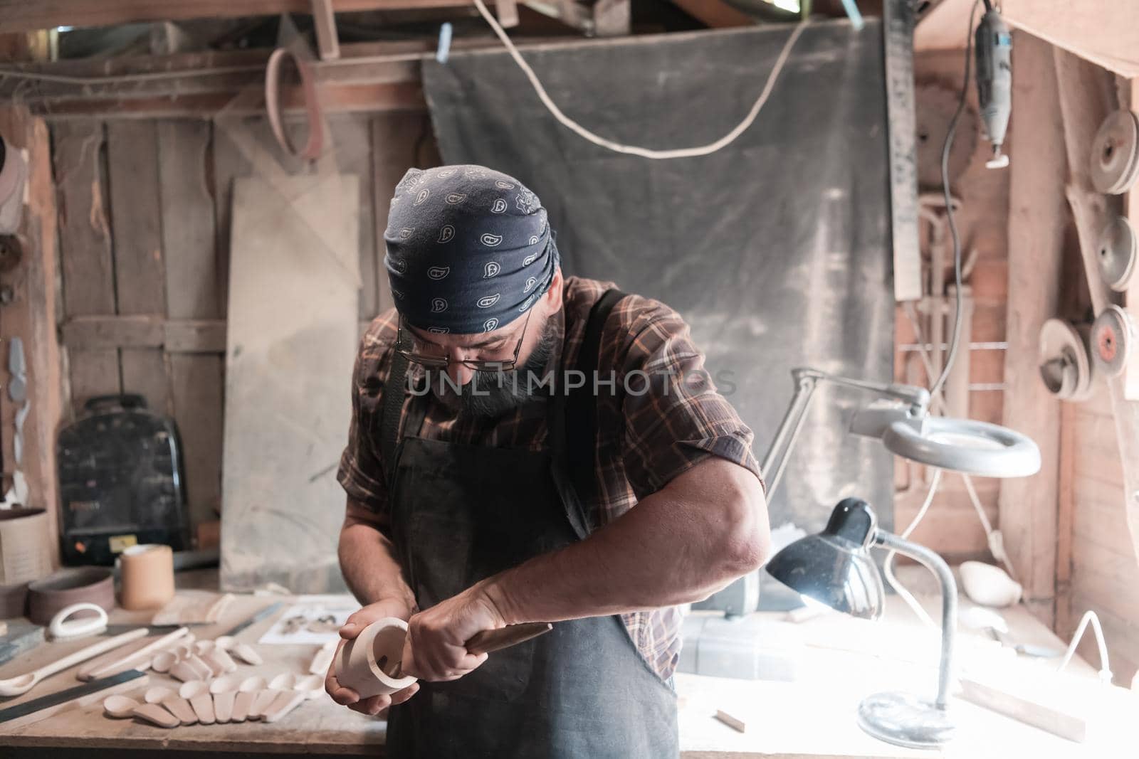 Spoon master in his workshop with wooden products and tools. High quality photo