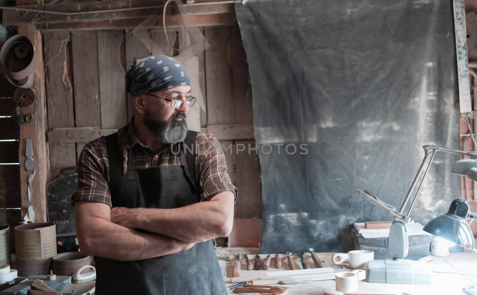 Spoon master in his workshop with wooden products and tools by dotshock