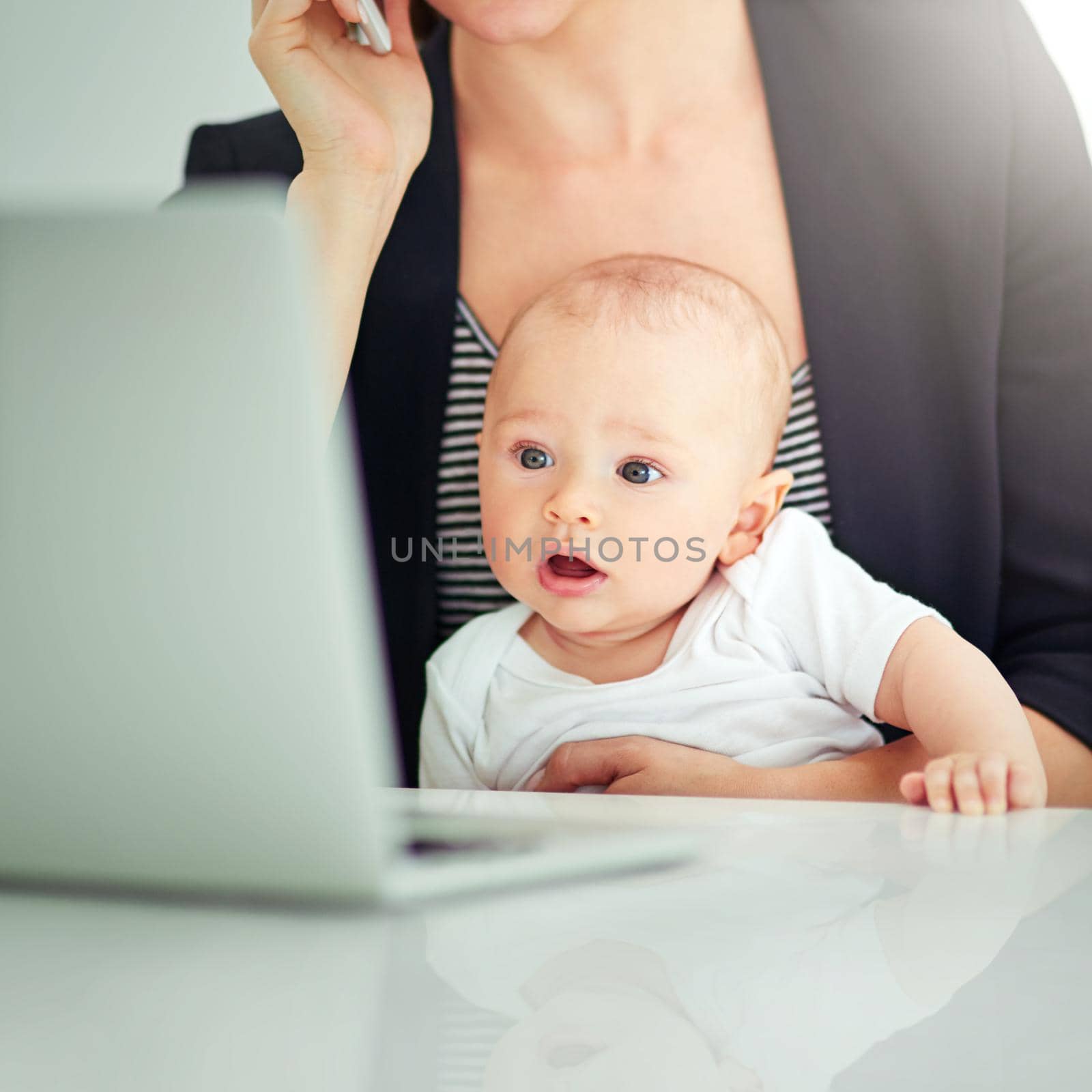 Shot of an adorable baby boy curious about his mothers work on her computer.