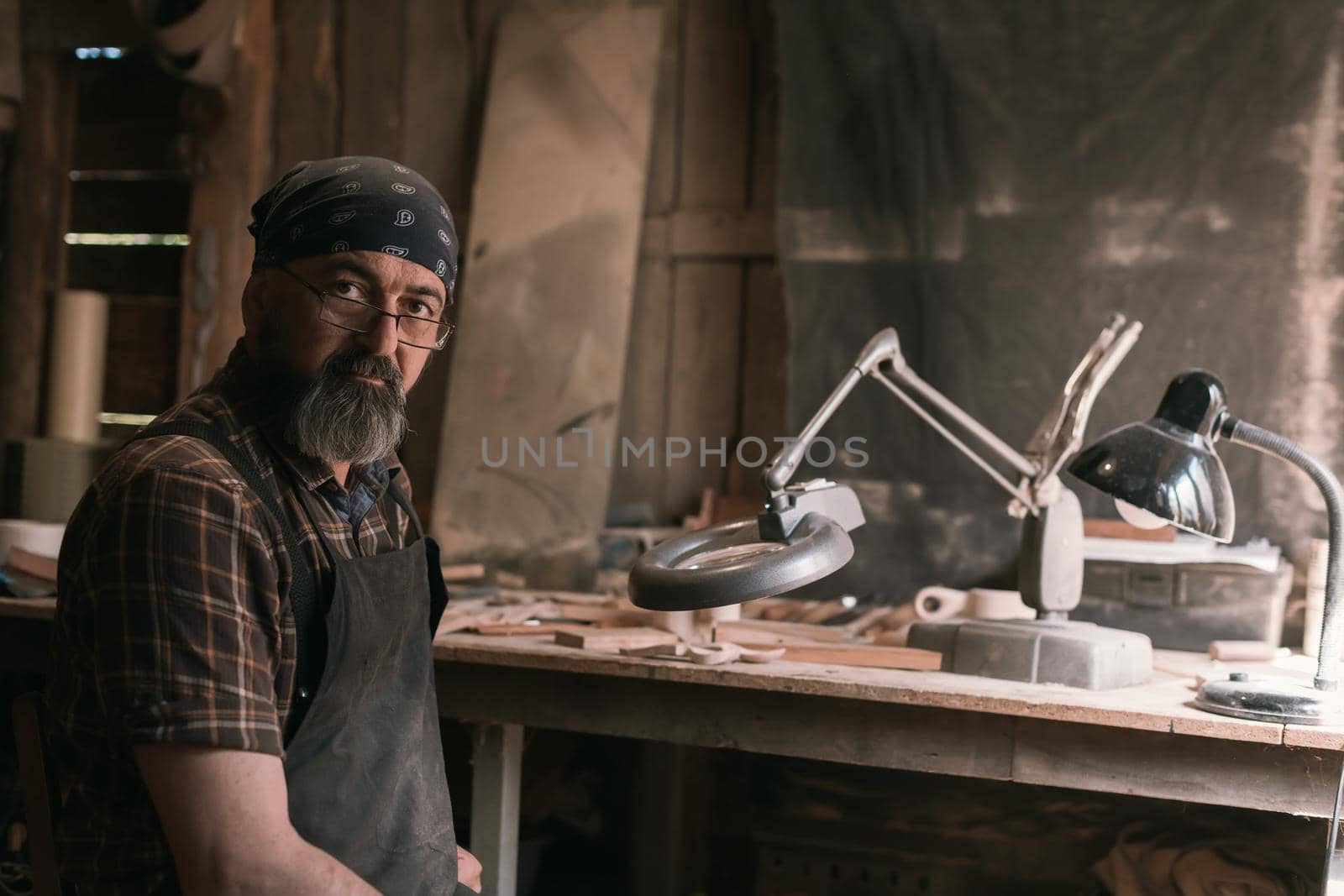 Spoon master in his workshop with wooden products and tools. High quality photo