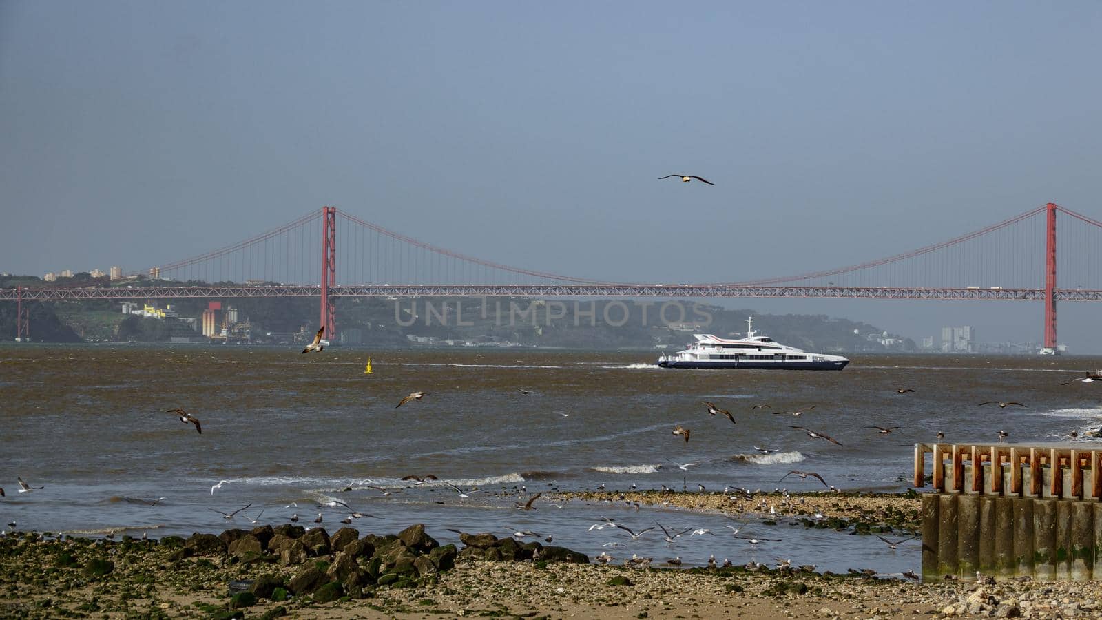 Long shot of 25 de Abril Bridge and boat in Lisbon over Tagus river