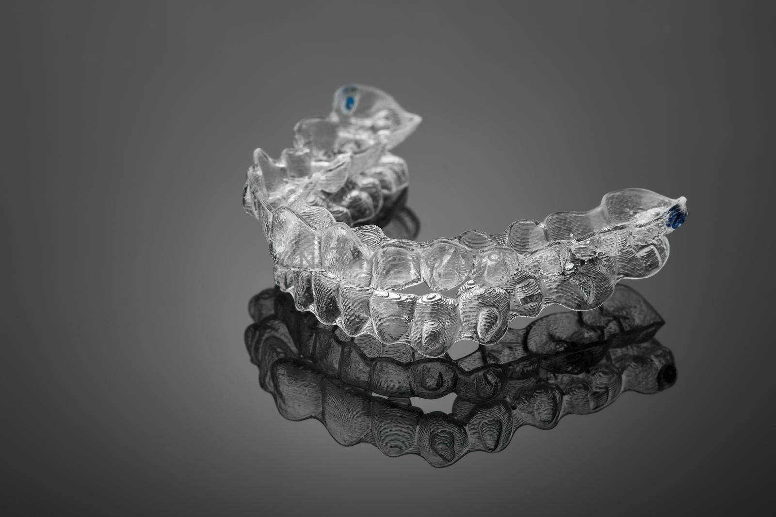 Invisible orthodontics cosmetic brackets on black background, tooth aligners, plastic braces. A way to have a beautiful smile and white teeth. by EvgeniyQW