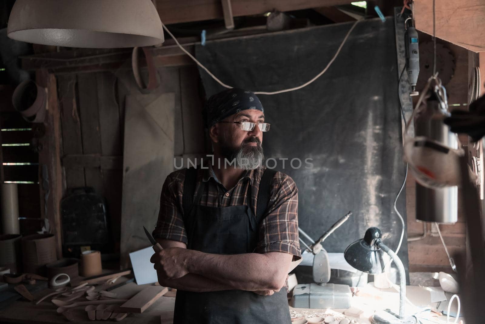 Spoon craft master in his workshop with handmade wooden products and tools by dotshock