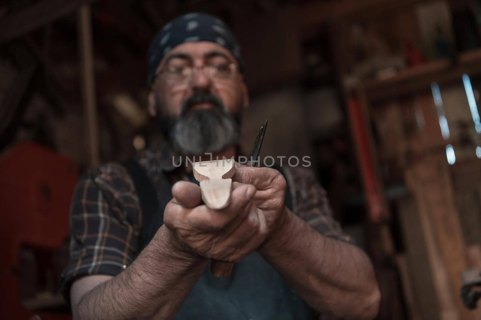 Spoon craft master in his workshop with handmade wooden products and tools working checking curve and line straight. High quality photo