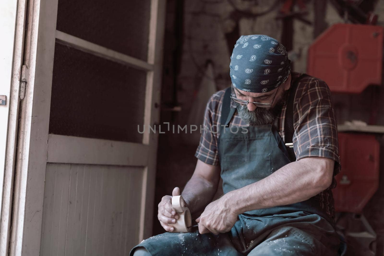 Spoon craft master in his workshop with handmade wooden products and tools working. High quality photo