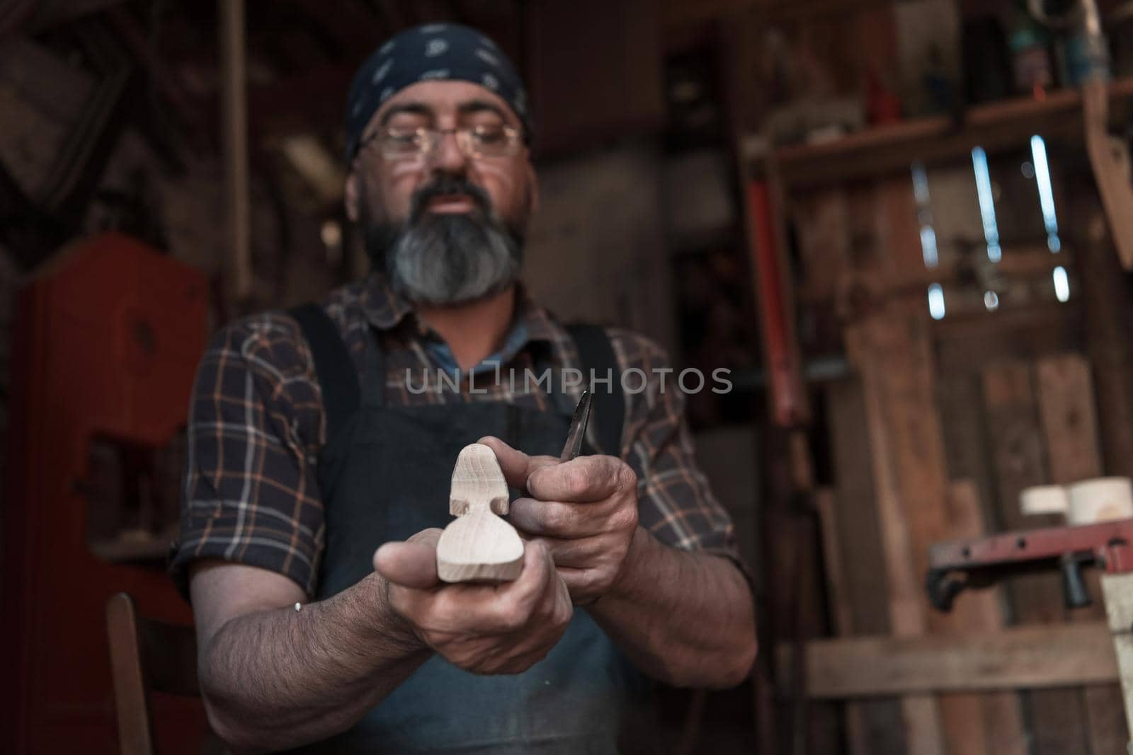 Spoon craft master in his workshop with handmade wooden products and tools working by dotshock