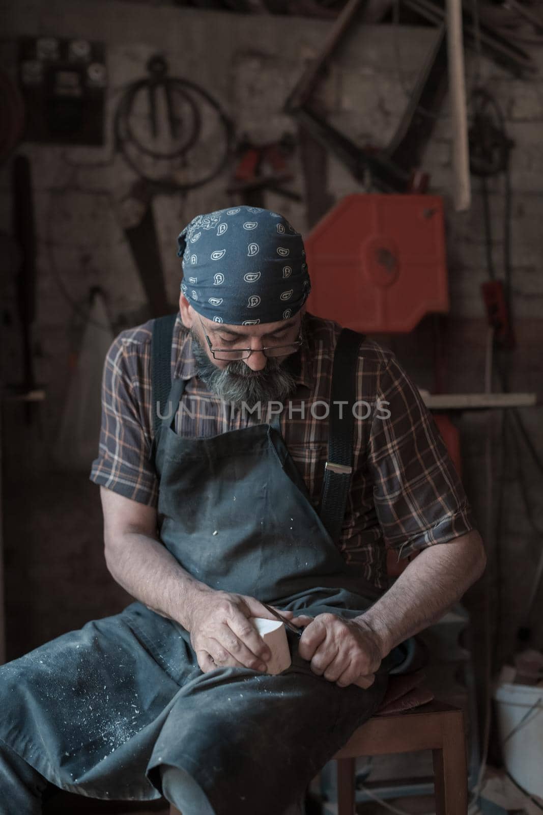 Spoon craft master in his workshop with handmade wooden products and tools working. High quality photo