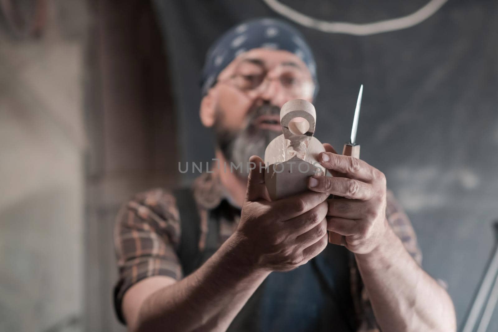 Spoon craft master in his workshop with handmade wooden products and tools working checking curve and line straight. High quality photo