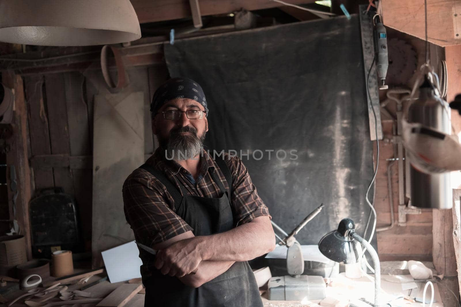 Spoon craft master in his workshop with handmade wooden products and tools. High quality photo