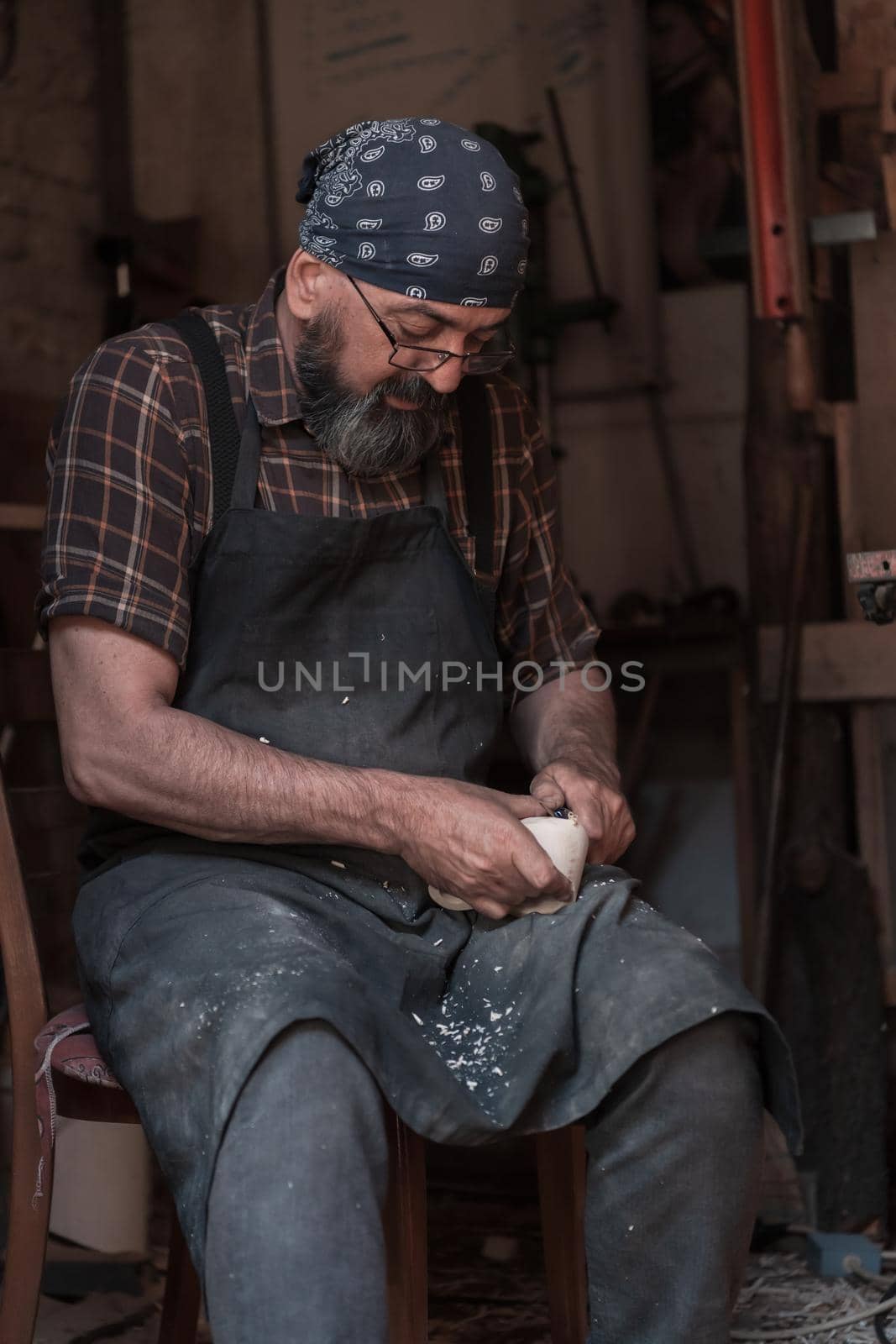 Spoon craft master in his workshop with handmade wooden products and tools working. High quality photo