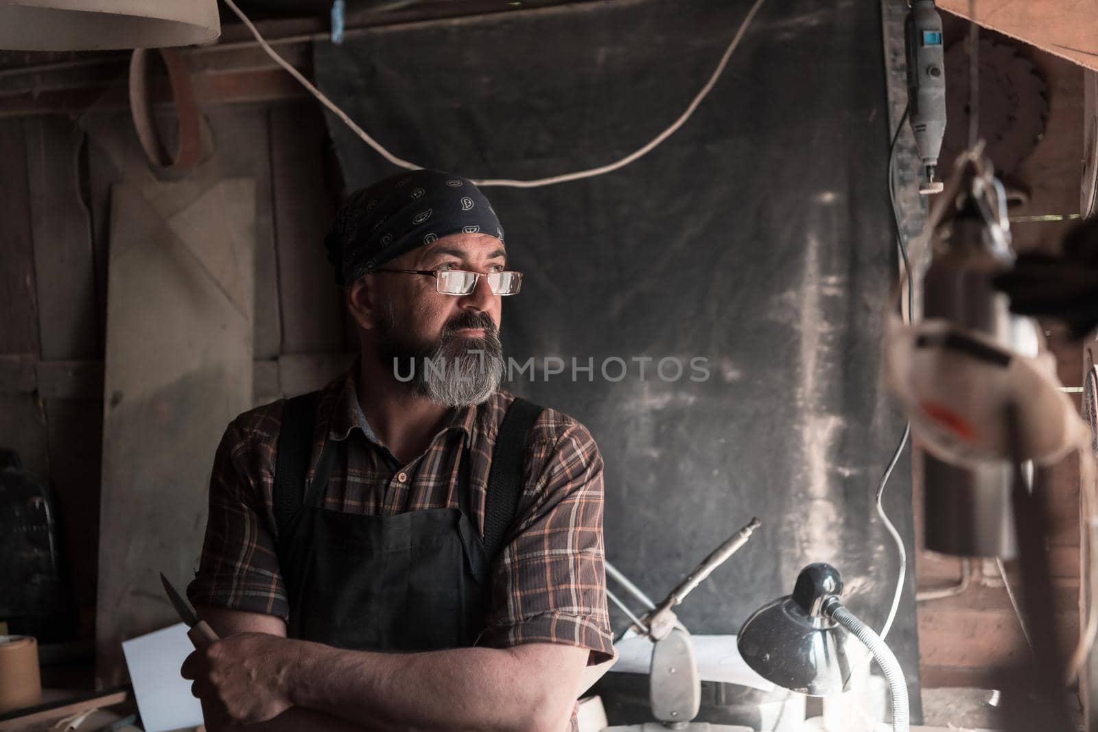 Spoon craft master in his workshop with handmade wooden products and tools. High quality photo