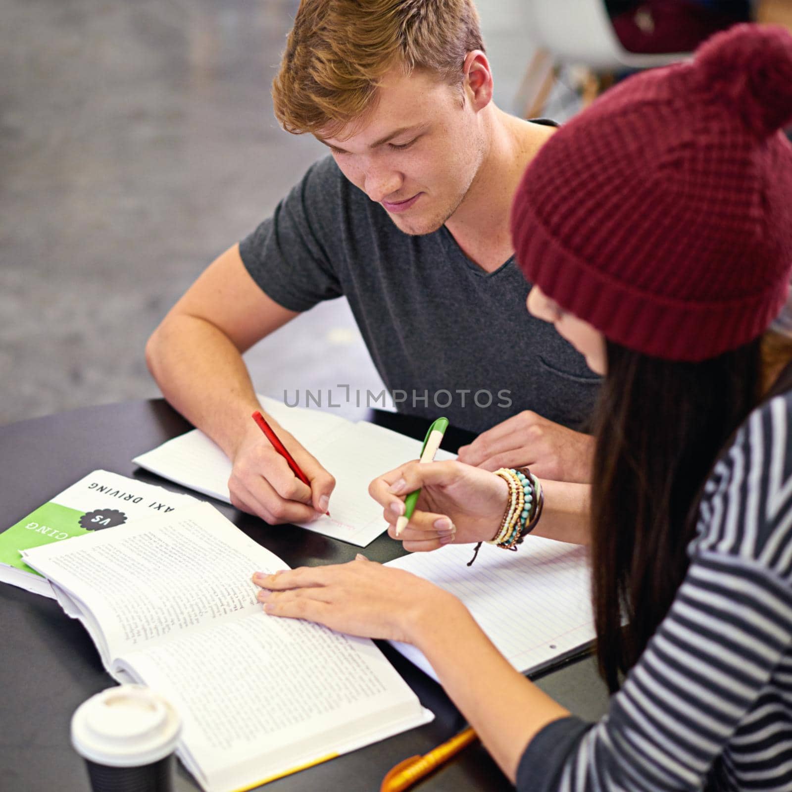 Wheres the fun in studying alone. Shot of two college students studying together at the library. by YuriArcurs