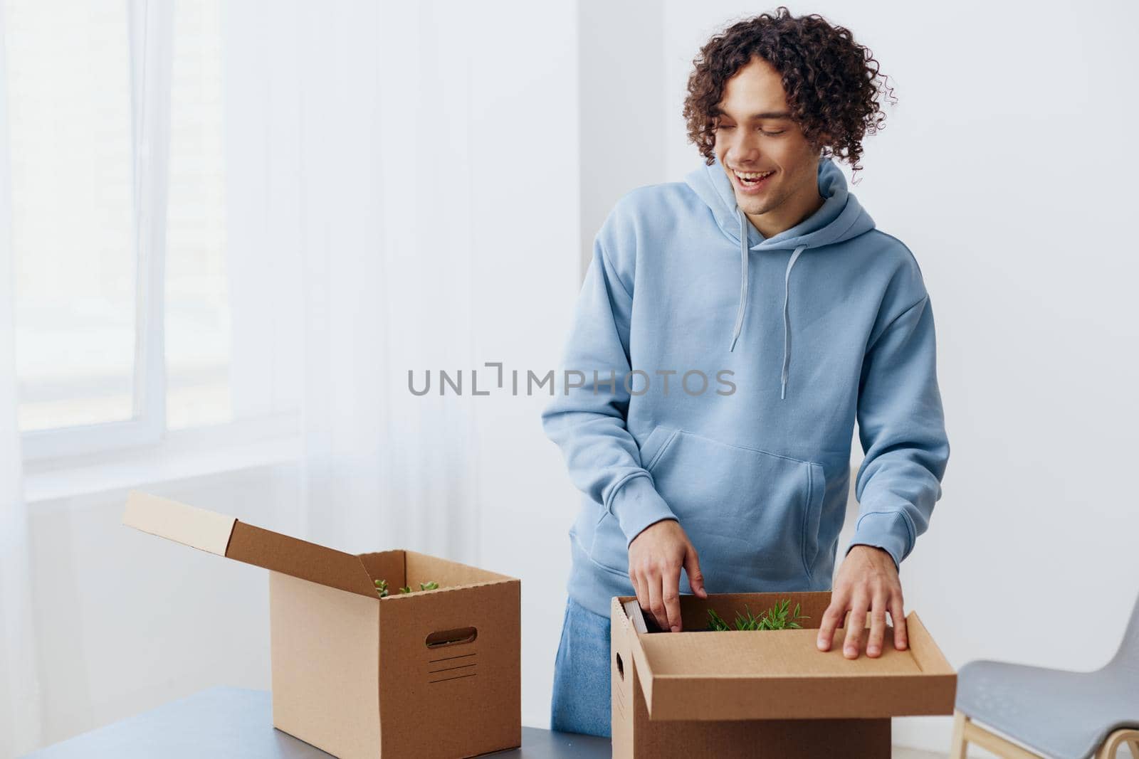 A young man unpacking things from boxes in the room interior. High quality photo