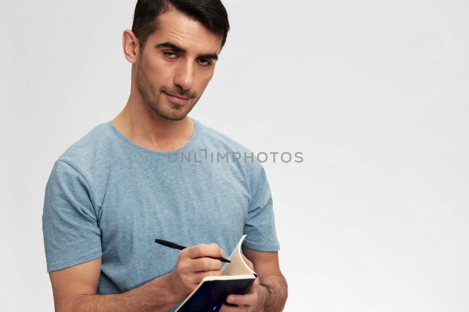 portrait man writes in a notebook t-shirt glasses lifestyle cropped view. High quality photo